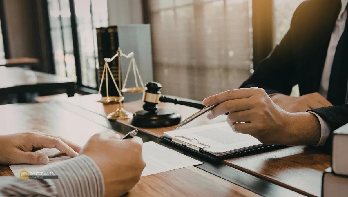 Brain injury attorney reviewing medical records and legal documents with a TBI client during a case consultation, with a gavel and scales of justice on the desk